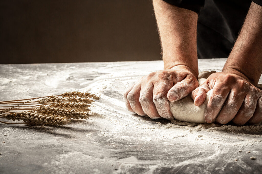 Hands of baker kneading dough isolated on black background. prepares ecologically natural pastries.